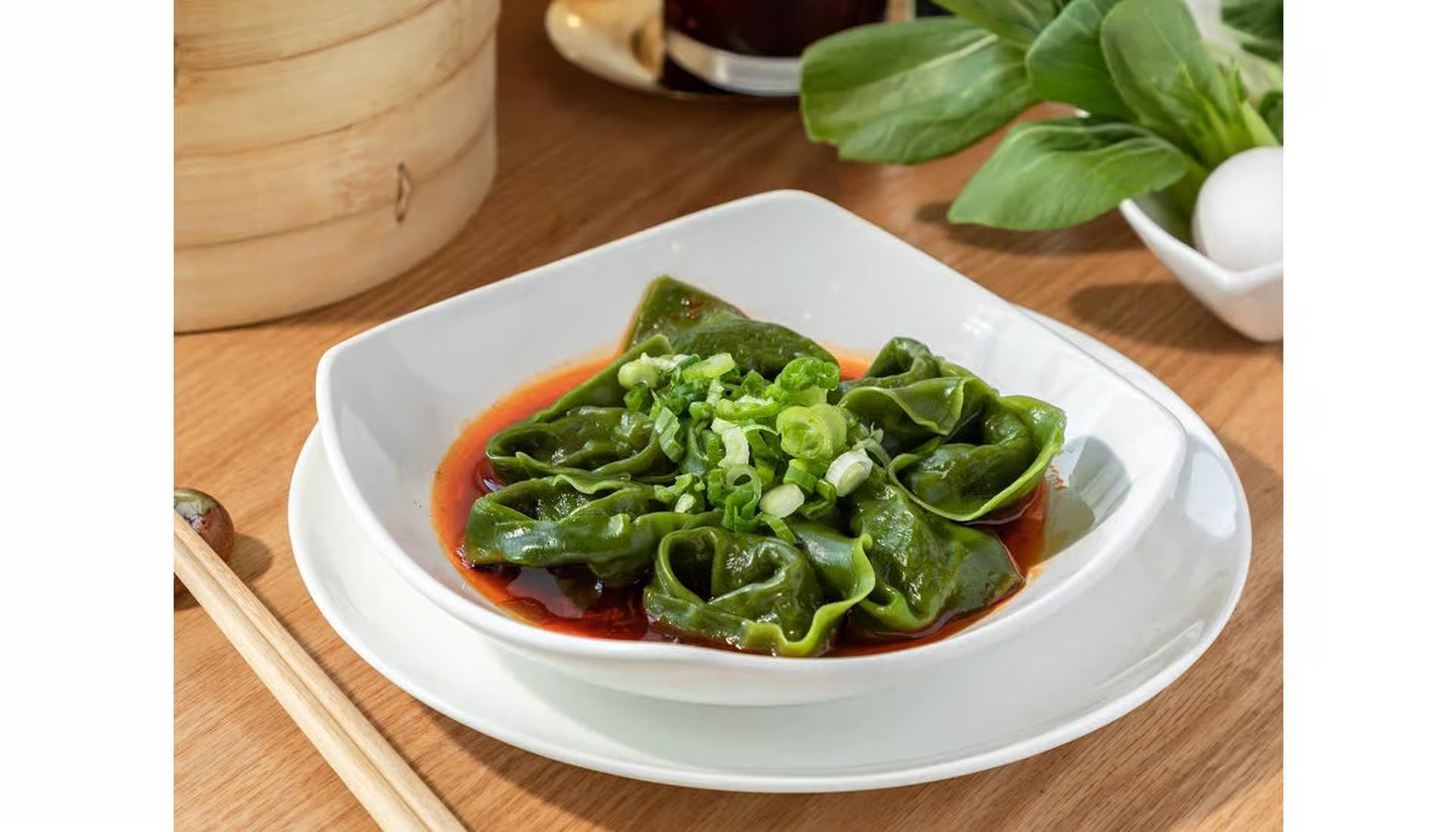 Spicy vegan wontons in red chili oil with green wrapper